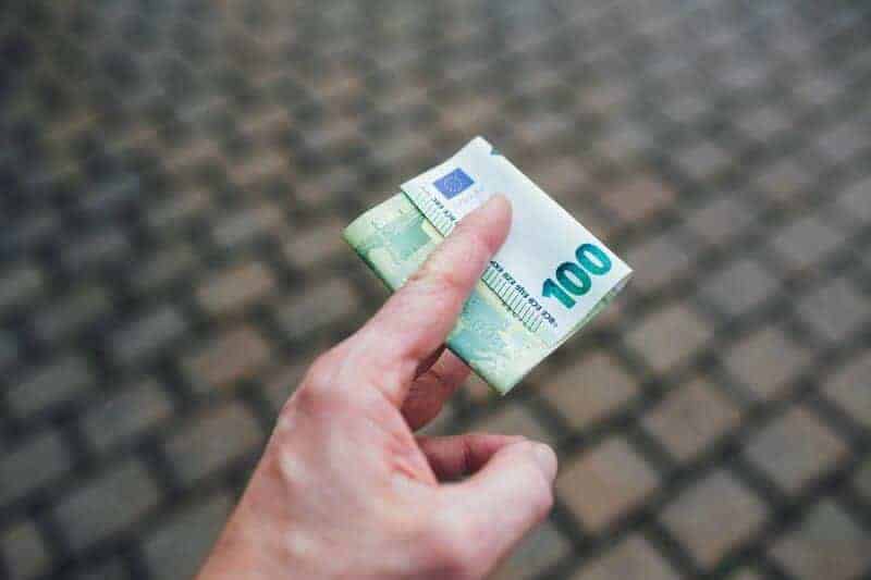 Mužská ruka drží sto eurovú bankovku